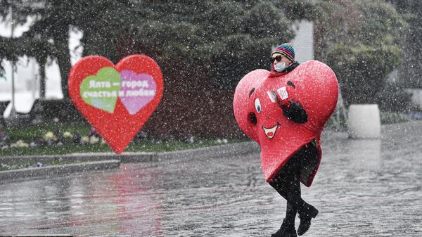 Мужчина в костюме в виде сердца на набережной Ялты во время снегопада