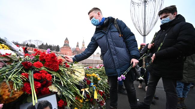 Молодые люди возлагают цветы на месте гибели политика Бориса Немцова на Большом Москворецком мосту в Москве