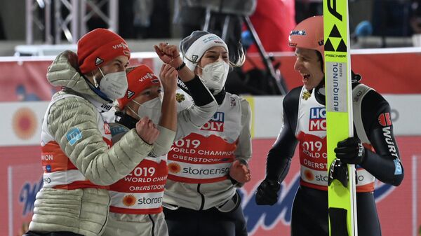 Germany's Karl Geiger (R) celebrates with (L-R) Germany's Markus Eisenbichler, Germany's Katharina Althaus and Germany's Anna Rupprecht after his jump in the Mixed Team HS106 hill jumping event at the FIS Nordic Ski World Championships in Oberstdorf, southern Germany, on February 28, 2021. (Photo by CHRISTOF STACHE / AFP)