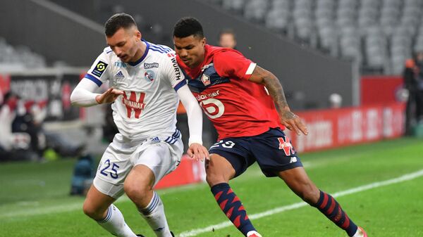 Lille's Mozambican defender Reinildo Mandava (R) fights for the ball with Strasbourg's French forward Ludovic Ajorque during the French L1 football match between Lille LOSC and Racing Club Strasbourg Alsace at the Pierre-Mauroy stadium in Villeneuve-d'Ascq, near Lille, northern France on February 28, 2021. (Photo by DENIS CHARLET / AFP)