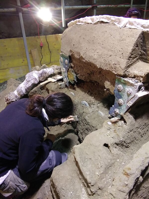 Археолог во время раскопок большой четырехколесной церемониальной колесницы, обнаруженной на месте древнеримского города Помпеи