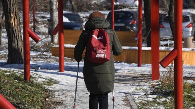 Женщина занимается скандинавской ходьбой в сквере на Океанском проспекте во Владивостоке