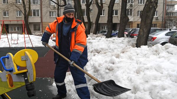 Сотрудник коммунальной службы убирает снег