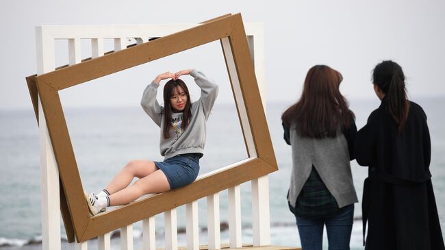 Девушки фотографируются на пляже Gyeongpo Beach в городе Каннын, Республика Корея