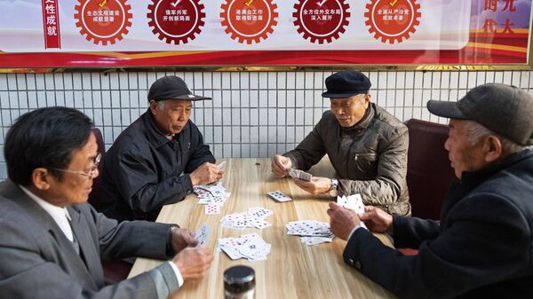 Пожилые мужчины играют в карты в городе Хуфу в провинции Цзянсу в Китае
