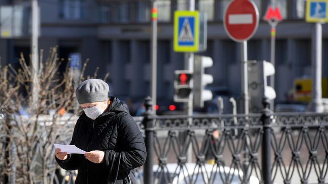 Женщина в защитной маске на одной из улиц в Москве