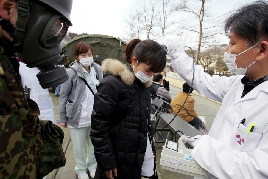 Сотрудник больницы проверяет людей на радиацию, после катастрофического землетрясения и цунами в Нихонмацу, Фукусима, северная Япония. 13 марта 2011 года