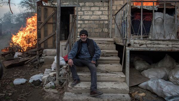 Местный житель Арег сидит у горящего дома в поселке Карегах, Нагорный Карабах. Некоторые жители сожгли свои дома перед тем как уйти