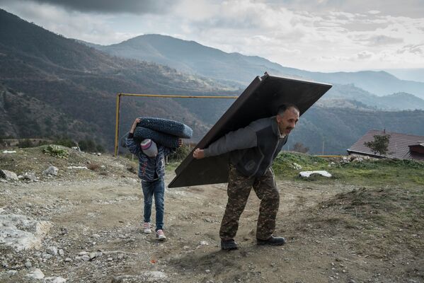 Мурад Мвргарян и его сын Ваак выносят вещи из своего дома перед тем, как покинуть город Лачин