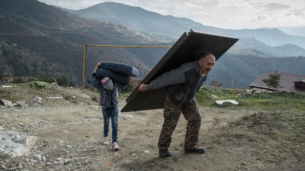 Мурад Мвргарян и его сын Ваак выносят вещи из своего дома перед тем, как покинуть город Лачин