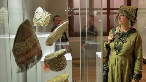 Посетительница осматривает один из экспонатов на открытии выставки Праздничная одежда народов России в Москве