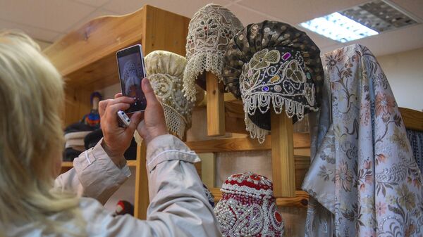 Посетитель фотографирует традиционные женские головные уборы - экспонаты краеведческого центра в Великом Новгороде