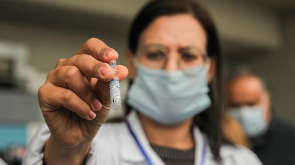 Медицинский работник демонстрирует ампулу с российской вакциной Спутник V 