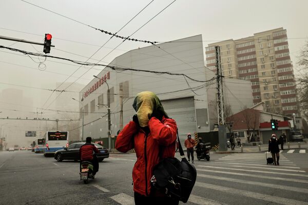 Женщина переходит дорогу во время песчаной бури в Пекине