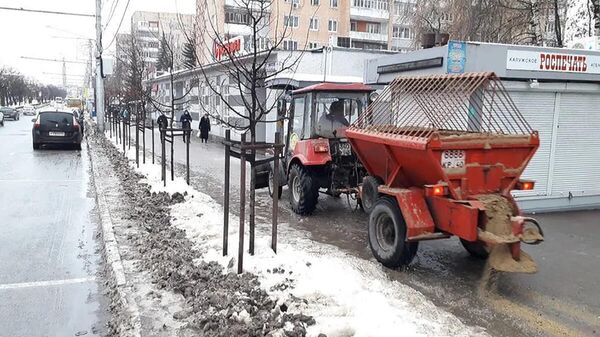 Сотрудники коммунальных служб посыпают песком тротуар в Калуге
