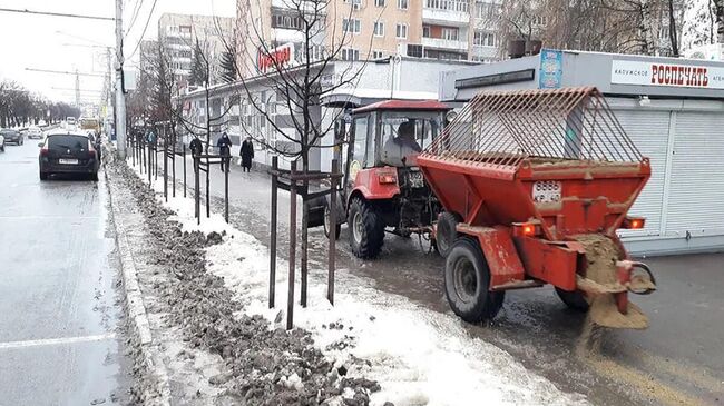 Сотрудники коммунальных служб посыпают песком тротуар в Калуге