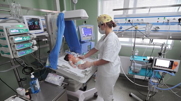 Медицинская сестра ведет уход за новорожденным в отделении реанимации и интенсивной терапии новорожденных (недоношенных детей) 