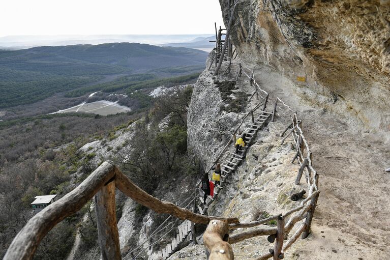 Туристы на территории объекта культурного наследия народов России федерального значения пещерного монастыря Челтер-Мармара, расположенного на обрыве горы Челтер-Кая