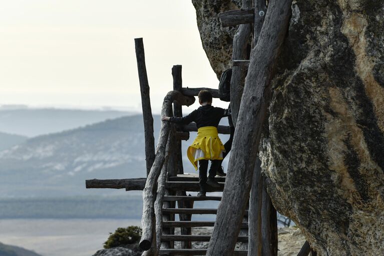 Туристы на территории объекта культурного наследия народов России федерального значения пещерного монастыря Челтер-Мармара, расположенного на обрыве горы Челтер-Кая