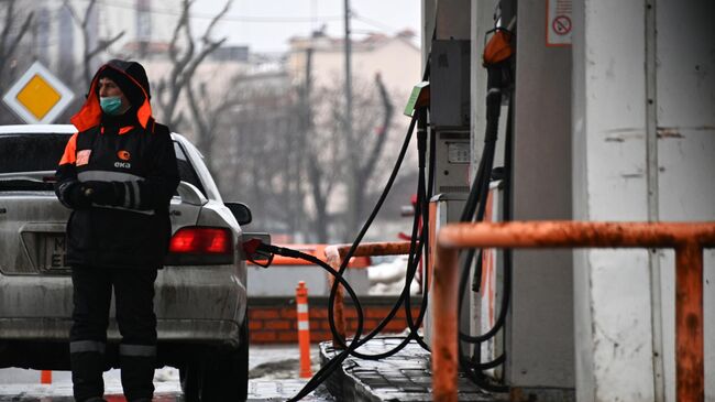 Заправщик заправляет автомобиль на одной из АЗС в Москве