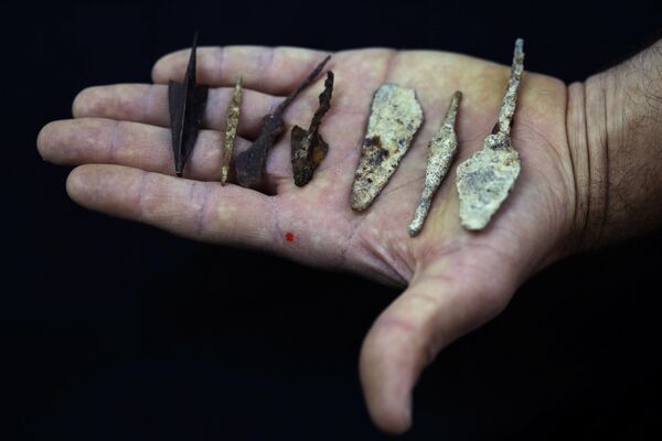 Сотрудник держит древние наконечники стрел и копий, недавно обнаруженных в пещерах Иудейской пустыни