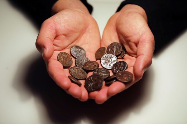Сотрудник держит древние монеты, недавно обнаруженных в пещерах Иудейской пустыни