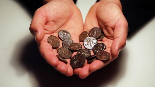 Сотрудник держит древние монеты, недавно обнаруженных в пещерах Иудейской пустыни