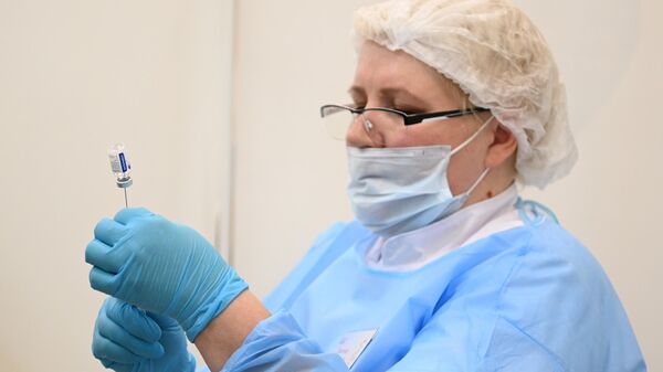 Медицинский сотрудник набирает в шприц российскую вакцину Спутник V