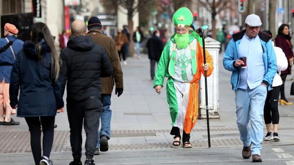Мужчина в костюме святого Патрика идет по улице О'Коннелл в Дублине, Ирландия
