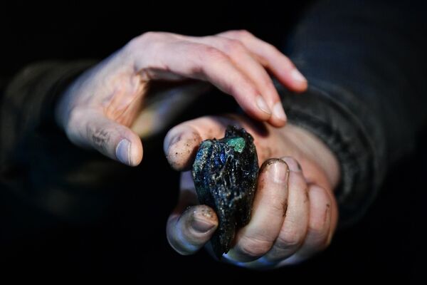 Рабочий демонстрирует горную породу с изумрудом в шахте Мариинского изумрудного прииска в Свердловской области