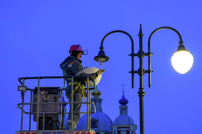 Специалист ОЭК проводит замену лампы на уличной опоре освещения