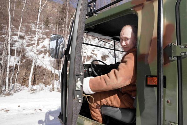 Президент РФ Владимир Путин управляет вездеходом во время прогулки в тайге