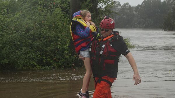 Спасатель переносит девочку во время наводнения в пригороде Сиднея Саквилл-Норт, Австралия