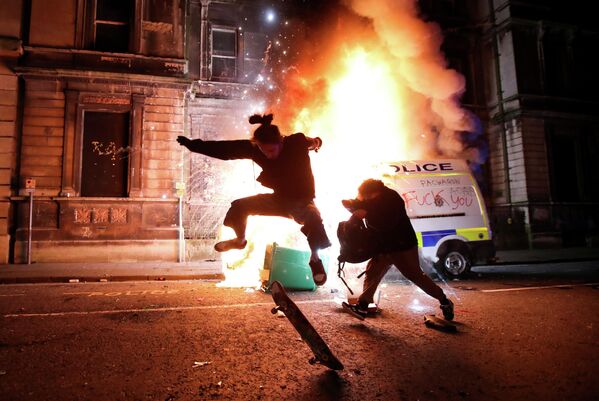 Демонстрант катается на скейтборде перед горящей полицейской машиной во время акции протеста против нового законопроекта о полиции, Бристоль, Великобритания