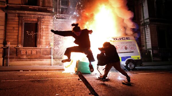 Демонстрант катается на скейтборде перед горящей полицейской машиной во время акции протеста против нового законопроекта о полиции, Бристоль, Великобритания