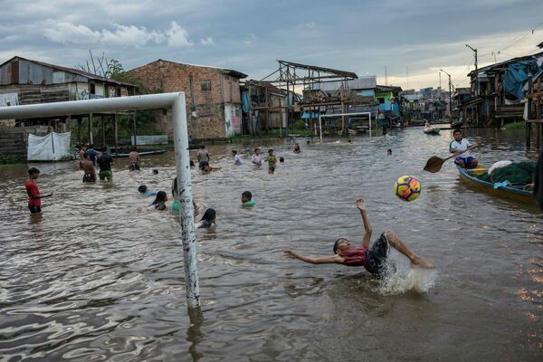 Мальчики играют в затопленном районе Икитоса в Перу