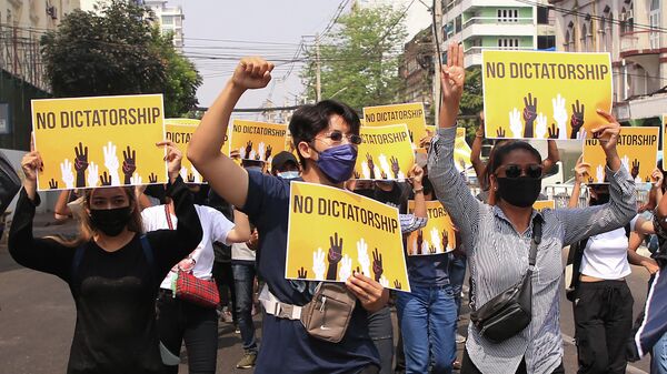 Люди с плакатами на демонстрации против военного переворота в Мьянме на улице города Янгон