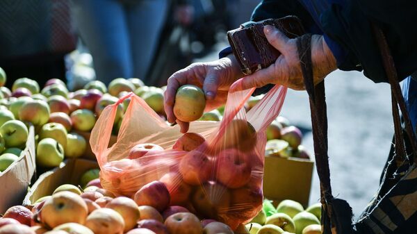 Женщина у прилавка с яблоками на сельскохозяйственной ярмарке