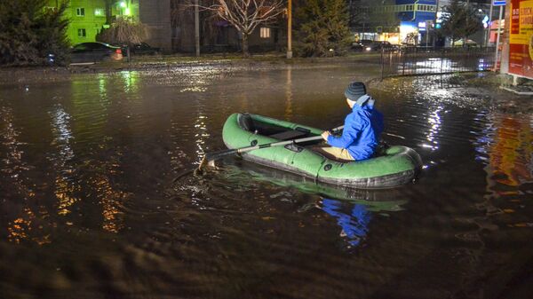 Жители города Таганрога перебираются через лужу на надувной лодке