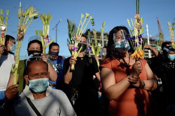 Люди во время мессы в Пальмовое воскресенье возле National Shrine of Our Mother of Perpetual Help в Паранаке, Филиппины
