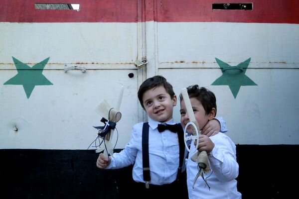 Мальчики празднуют Пальмовое воскресенье у церкви в Дамаске, Сирия