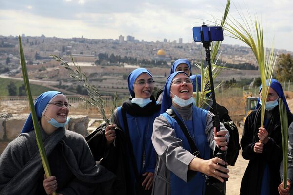 Монахини делают селфи во время празднования Пальмового воскресенья на Елеонской горе в Иерусалиме