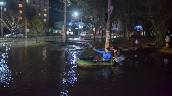 Жители города Таганрога перебираются через лужу на надувной лодке