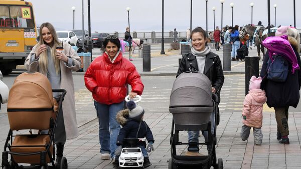 Женщины с детьми гуляют на набережной Спортивной гавани во Владивостоке