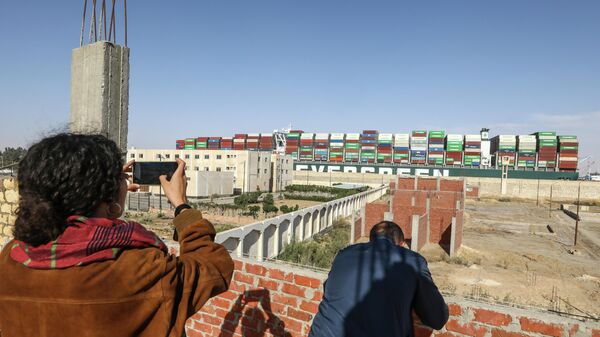 Люди фотографируют контейнеровоз Ever Given, покидающий Суэцкий канал 