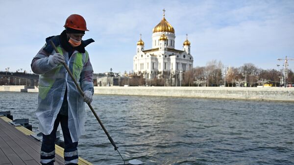Сотрудник ГБУ Гормост красит причал на набережной Москва-реки