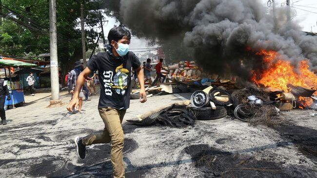 Участники акции протеста против военного переворота сжигают баррикады в Янгоне, Мьянма