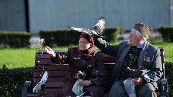 Пожилые люди кормят голубей