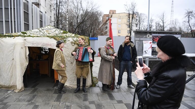 Женщина фотографирует артистов у станции Народное ополчение Большой кольцевой линии московского метрополитена.