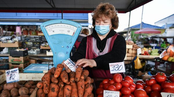 Продавец за прилавком с овощами на рынке в Симферополе